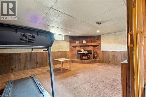 Brick fireplace with a wood mantel, wood paneling, and carpet flooring - 135 Cedarhill Crescent, Kitchener, ON 