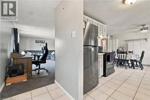 Kitchen area with tile flooring and a ceiling fan, featuring a black refrigerator and stove - 135 Cedarhill Crescent, Kitchener, ON 