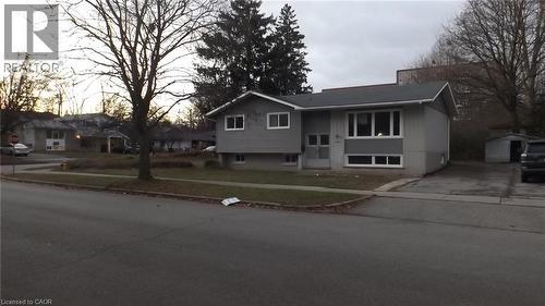 Split-level residence featuring a gray exterior, white window trim, and a dark shingle roof - 68 Austin Drive, Waterloo, ON 
