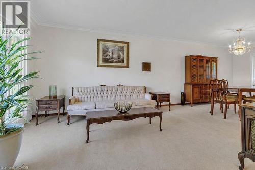 Neutral tone wall paint, light neutral carpeting, crown molding, and a crystal chandelier - 2344 Brinell Avenue, Burlington, ON 