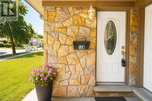 Stone veneer exterior with a white front door featuring an oval-shaped decorative glass insert, complemented by an overhead exterior light fixture - 136 Jansen Avenue, Kitchener, ON 