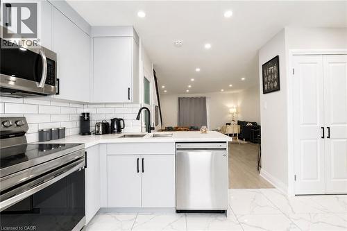 White shaker-style cabinetry with matte black hardware, stainless steel appliances, white subway tile backsplash, white countertop, and recessed lighting - 136 Jansen Avenue, Kitchener, ON 