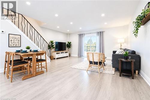 Open-concept living area featuring light wood-finish flooring, recessed lighting, and a contemporary staircase with a black metal railing - 136 Jansen Avenue, Kitchener, ON 