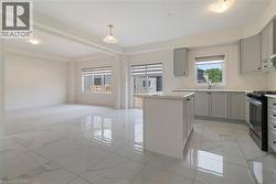Kitchen featuring gas range oven, gray cabinetry, light marble finish flooring, a center island, and light countertops - 