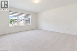 Neutral carpeting, white wall paint, window with horizontal blinds, flush mount ceiling light, and white trim - 