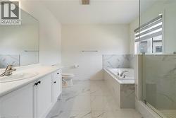Bathroom with vanity, a garden tub, marble look tile flooring, and a marble finish shower - 
