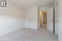 Unfurnished bedroom with light colored carpet and baseboards - 