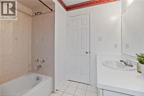 White tile flooring, white vanity with integrated sink, chrome faucet, wall-mounted mirror, and a bathtub with tile surround - 1263 Bantham Street, Mississauga, ON 