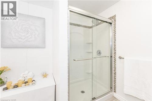 Glass-enclosed shower with a chrome fixture, integrated shelving, and mosaic tile detailing - 388 Appleby Line, Burlington, ON 