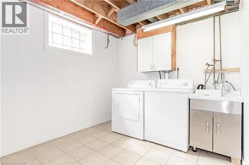 Laundry area featuring tile flooring, a utility sink with a stainless steel cabinet, and a built-in storage cabinet - 388 Appleby Line, Burlington, ON 
