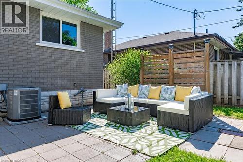 Paved patio area, brick exterior, white window trim, wooden privacy fence, green lawn - 388 Appleby Line, Burlington, ON 