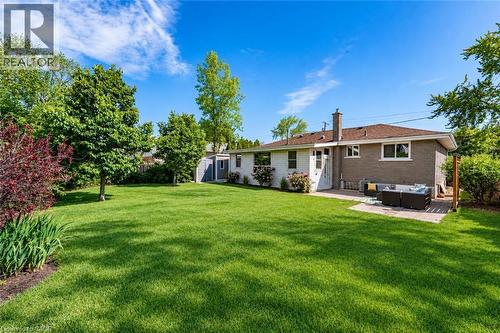 Expansive lawn area with mature trees, brick exterior, dedicated patio space, and a storage shed - 388 Appleby Line, Burlington, ON 