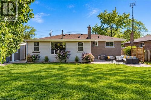 Expansive rear lawn, paved patio area, white siding, brick exterior, and a detached storage shed - 388 Appleby Line, Burlington, ON 