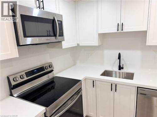White cabinetry with black hardware, stainless steel appliances, white countertops, and an undermount sink with a matte black faucet - 304 Westpark Crescent, Waterloo, ON 