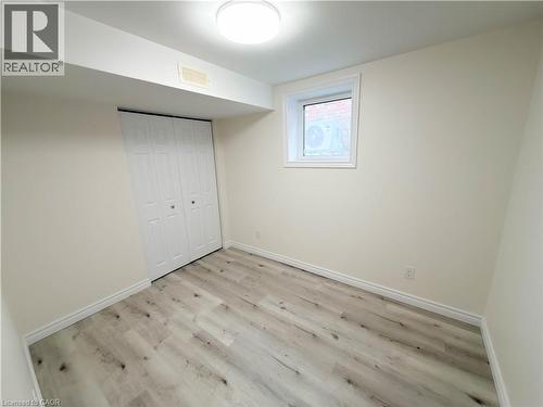 Light wood-finish flooring, white bi-fold doors, white trim, and recessed window - 304 Westpark Crescent, Waterloo, ON 