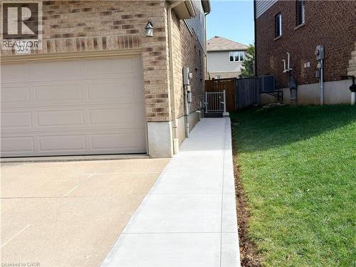 Brick exterior with attached garage, concrete driveway, and side walkway with privacy gate - 304 Westpark Crescent, Waterloo, ON 