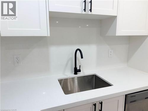 White shaker-style cabinetry with matte black hardware, solid surface countertops, and a stainless steel undermount sink with a matte black gooseneck faucet - 304 Westpark Crescent, Waterloo, ON 