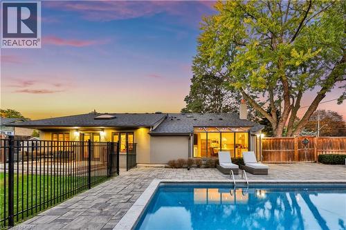 Paver patio surrounding a rectangular swimming pool, featuring a black metal fence and a wood fence - 52 Joymar Drive, Mississauga, ON 