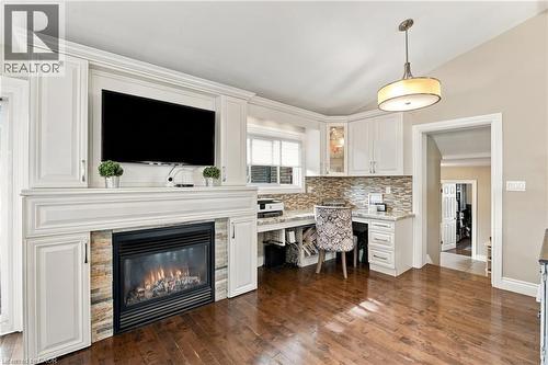 Built-in fireplace with stone surround, custom built-in cabinetry, wood-finish flooring, recessed lighting, and a dedicated workspace with upper and lower storage - 617 Scenic Drive, Hamilton, ON 