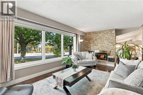 Wide picture window, stone-finish fireplace surround, dark wood-finish flooring, recessed lighting - 617 Scenic Drive, Hamilton, ON 