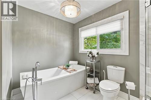 Freestanding tub with floor-mounted faucet, white framed window, and a chandelier light fixture - 617 Scenic Drive, Hamilton, ON 