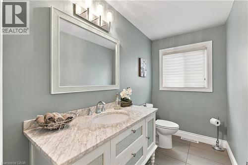 Vanity with a light-toned countertop and integrated sink, chrome faucet, and a framed mirror - 617 Scenic Drive, Hamilton, ON 