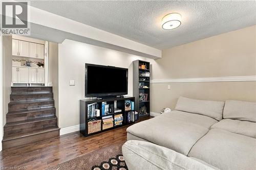 Wood-finish flooring with a media wall, built-in shelving, and crown molding - 617 Scenic Drive, Hamilton, ON 