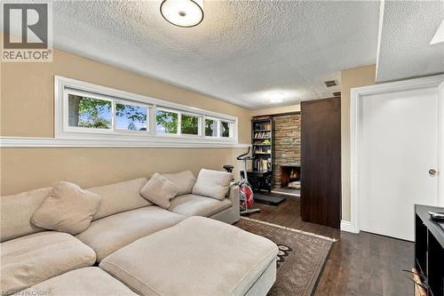Recessed lighting illuminates the space, featuring wood-finish flooring and a stone-clad fireplace - 617 Scenic Drive, Hamilton, ON 