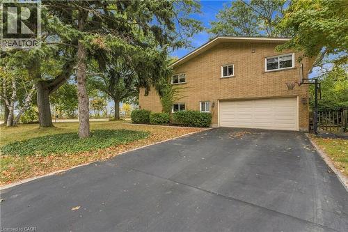 Brick exterior with a large driveway, two-car garage, and mature trees - 617 Scenic Drive, Hamilton, ON 