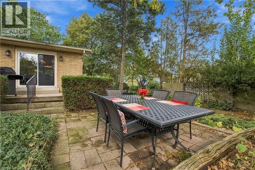 Brick exterior with sliding glass door access to a multi-level stone patio - 617 Scenic Drive, Hamilton, ON 