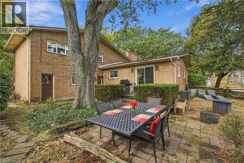 Brick exterior with a large mature tree, stone paver patio, and sliding glass door - 617 Scenic Drive, Hamilton, ON 