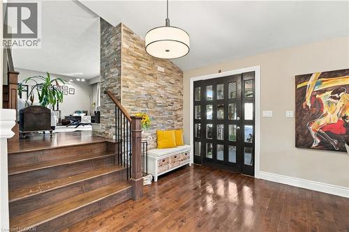 Hardwood flooring throughout the entry, a stacked stone accent wall, and a black multi-pane front door - 617 Scenic Drive, Hamilton, ON 