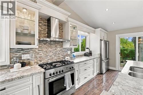 White cabinetry, stainless steel appliances, granite countertops, wood-finish flooring, and a mosaic tile backsplash - 617 Scenic Drive, Hamilton, ON 