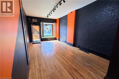 Hardwood flooring, exposed brick walls, track lighting, prominent front window, and a glass-paneled entry door - 319 King Street E, Hamilton, ON 