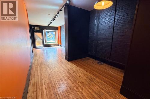 Wood-finish flooring throughout, track lighting, exposed brick accent wall, and storefront window - 319 King Street E, Hamilton, ON 