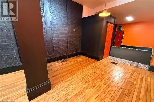 Hardwood flooring throughout, exposed brick wall, overhead pendant lighting, and a vibrant accent wall - 319 King Street E, Hamilton, ON 