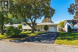 Charming single-story home featuring a circular driveway, two-car garage, and mature landscaping with established trees providing natural shade - 