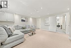 Spacious finished basement featuring neutral carpeting, recessed lighting throughout, and abundant natural light from multiple windows - 