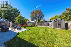 Expansive green lawn, concrete patio, privacy fencing, mature trees, and a detached storage shed - 