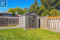 Enclosed backyard featuring a storage shed, wooden fencing, and a stone-edged garden bed - 