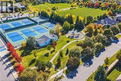 Residential property with a light-colored exterior and a dark roof, situated beside multiple tennis courts - 