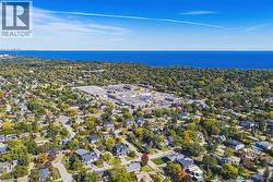 Aerial perspective of a residential neighborhood with mature trees, commercial establishments, and a visible body of water - 