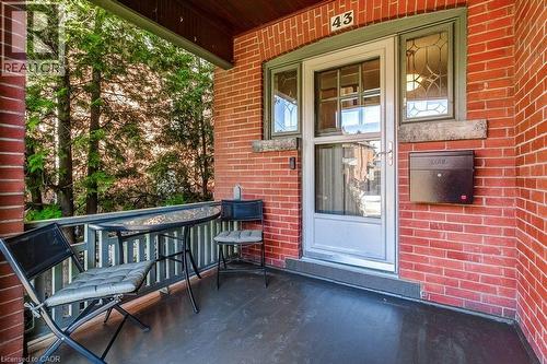 Brick exterior featuring a covered porch, wood ceiling, and decorative glass transom - 43 Rosslyn Avenue S, Hamilton, ON 
