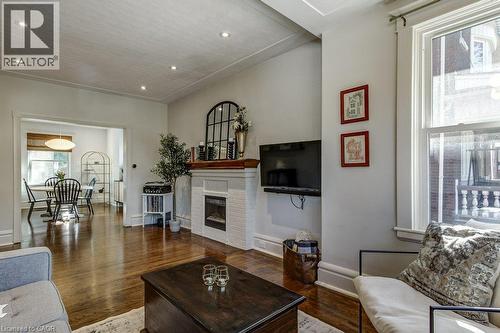 Warm wood-finish flooring complements the white brick fireplace and mantel - 43 Rosslyn Avenue S, Hamilton, ON 