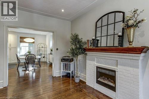 White brick fireplace with a wood mantel, wood-finish flooring, and recessed lighting - 43 Rosslyn Avenue S, Hamilton, ON 
