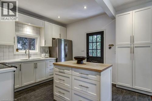 Kitchen featuring white shaker-style cabinetry, a central island with a wood-finish countertop, stainless steel appliances, and a tiled backsplash - 43 Rosslyn Avenue S, Hamilton, ON 