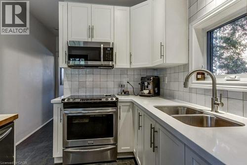 White shaker cabinetry, stainless steel appliances, dual basin undermount sink, solid surface countertops, and a subway tile backsplash - 43 Rosslyn Avenue S, Hamilton, ON 