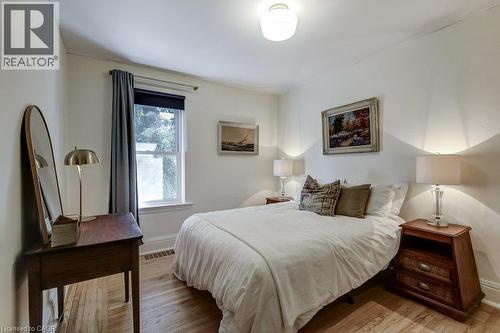 Hardwood flooring, painted white walls, single window with roller shade and drapes, and a ceiling-mounted light fixture - 43 Rosslyn Avenue S, Hamilton, ON 