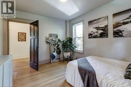Light wood-finish flooring, white walls, and a single-pane window - 43 Rosslyn Avenue S, Hamilton, ON 