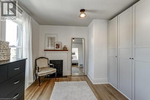 Hardwood flooring, fireplace with brick surround and tile hearth, built-in cabinetry, and window with white trim - 43 Rosslyn Avenue S, Hamilton, ON 